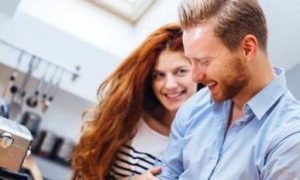 couple stands in kitchen happily laughing