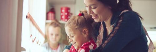 woman happily plays with daughter while another little girl sitting looking at home