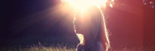 woman stands under shining sun thinking