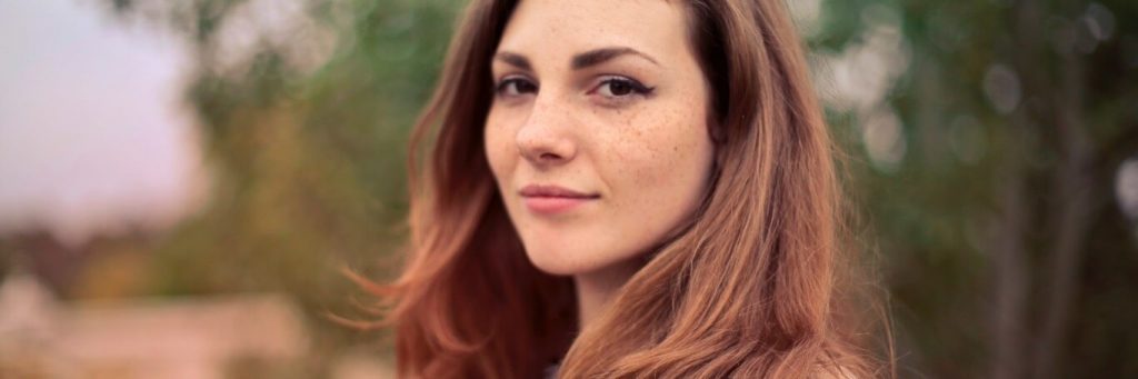 young woman in forest smiles