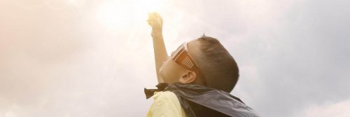 man wearing sunglass raises hand in sunny sky