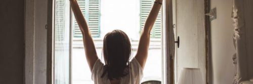 woman facing backward opens window