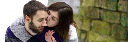 man carries girlfriend on back while woman kissing on cheek