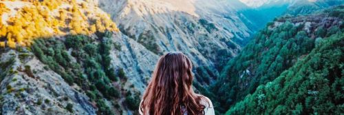 woman facing backward watches beautiful hills