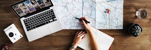 woman hands holding black pen pointing at map next to laptop glass of water