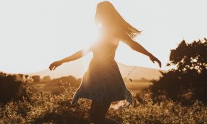 girl happily walking in field feeling grateful in sunny sky