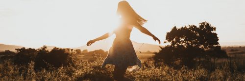 girl happily walking in field feeling grateful in sunny sky