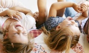 happy family lies on bed talking laughing playing with each other