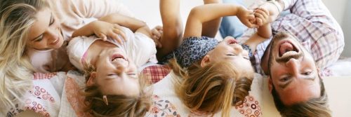 happy family lies on bed talking laughing playing with each other