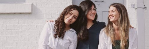 three women standing side by side smiling