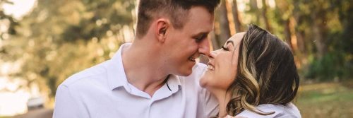 couple happily smiles hugging walking on street along forest in beautiful sunny sky