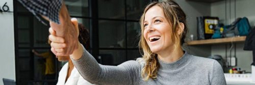 woman sits in office shaking hand with college