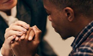 man sad face holding hands being comfort by college