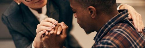 man sad face holding hands being comfort by college