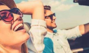 couple sits in car man happily drives while girlfriend smiling enjoying nice weather