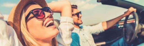 couple sits in car man happily drives while girlfriend smiling enjoying nice weather