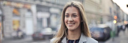 woman walks alone on busy city street happily smiling