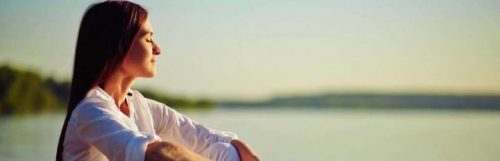 woman sits closing eyes focusing on breathing meditation