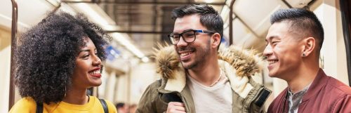 group of friends happily smiling talking in public train station