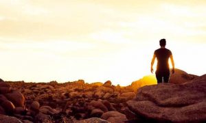 man walking between rocks in sunny sky