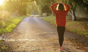 woman hands on hair walked along footpath between bushes in beautiful sunny weather