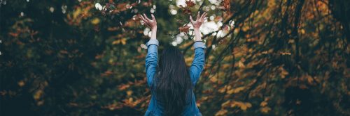 woman stands in forest facing backward gratitude life