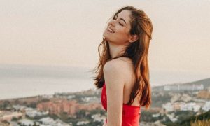 young woman happy face stands on rock feeling grateful about life