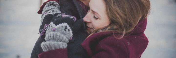 woman wearing gloves jacket hugging another person