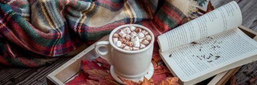 book white mug with mini stone on plate beside blanket