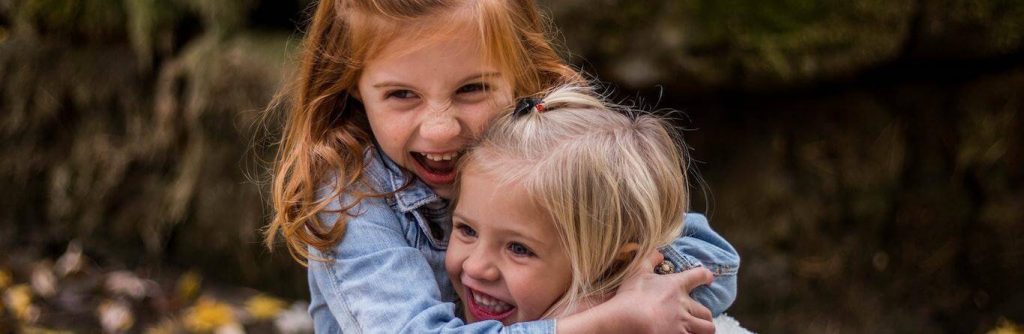 two girls hugs happily smile have fun at each other