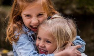 two girls hugs happily smile have fun at each other