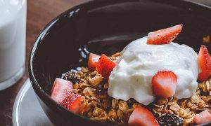 strawberry yogurt cereal breakfast bowl beside glass of milk