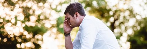 man sits hand in face feeling sad worried painful overthinking