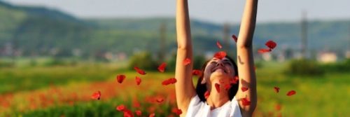 woman stands on field raising hands feeling fulfilling in life