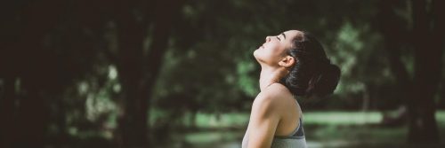 woman stands in forest eyes closed focuses on breathing practicing inner peace