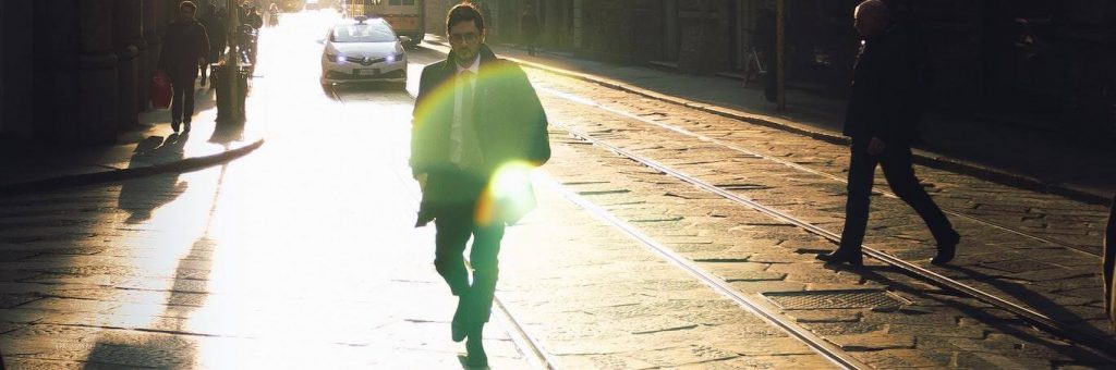 businessman walks alone on street beside railway