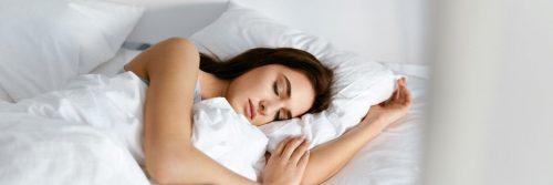 woman sleeping well tightly on bed beside white pillows