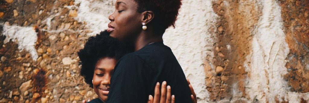 two curly hair woman happily hug each other