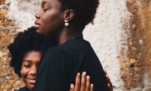 two curly hair woman happily hug each other