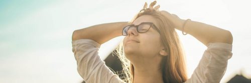 woman stands hand on hair eyes closed gratitude life