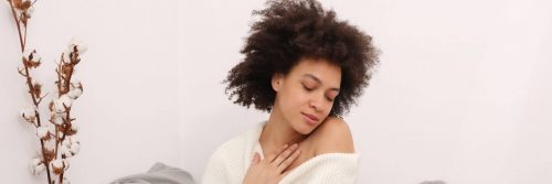 curly black hair woman closed eyes hand on chest feeling loved herself