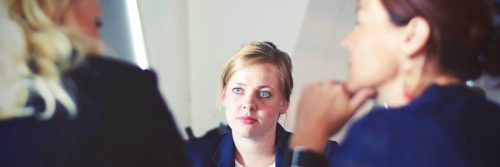 woman looks at two colleges talking in office