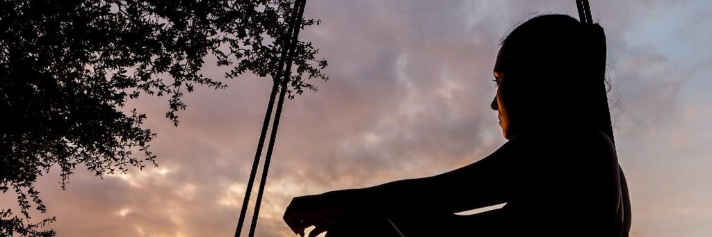 woman sits on hammock looking at dark cloudy sky