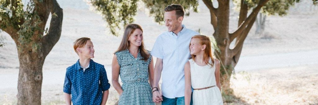 happy family walks in park smiling enjoying joyful moment while parents holding hands