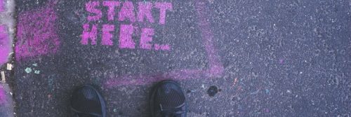 dark shoes stepping on purple sign detailing start here