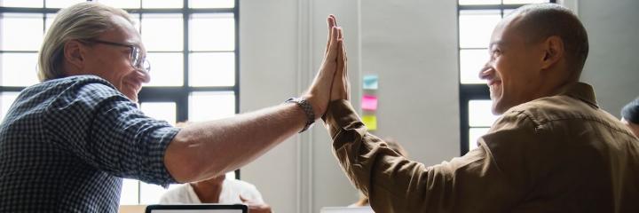 two men clap hands happily greeting