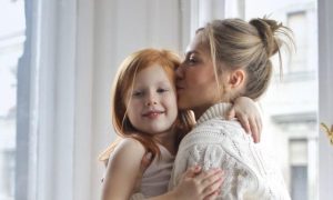 mother carrying kissing little adorable daughter