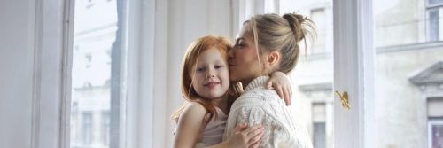 mother carrying kissing little adorable daughter