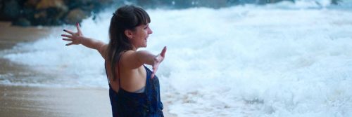 woman stands on beach happily smiling gratitude life looking at waves