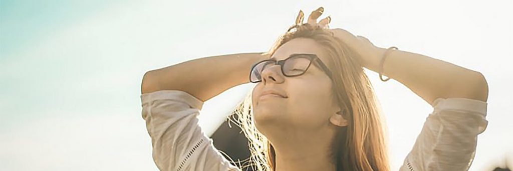 woman stands hand on hair eyes closed gratitude life